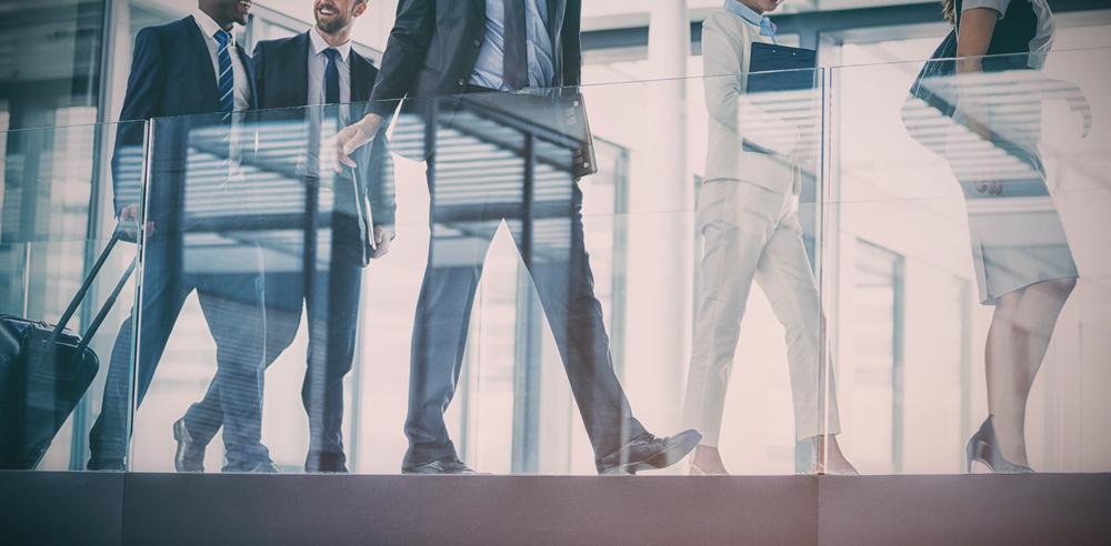 Business professionals walking through an office lobby with reflections in glass